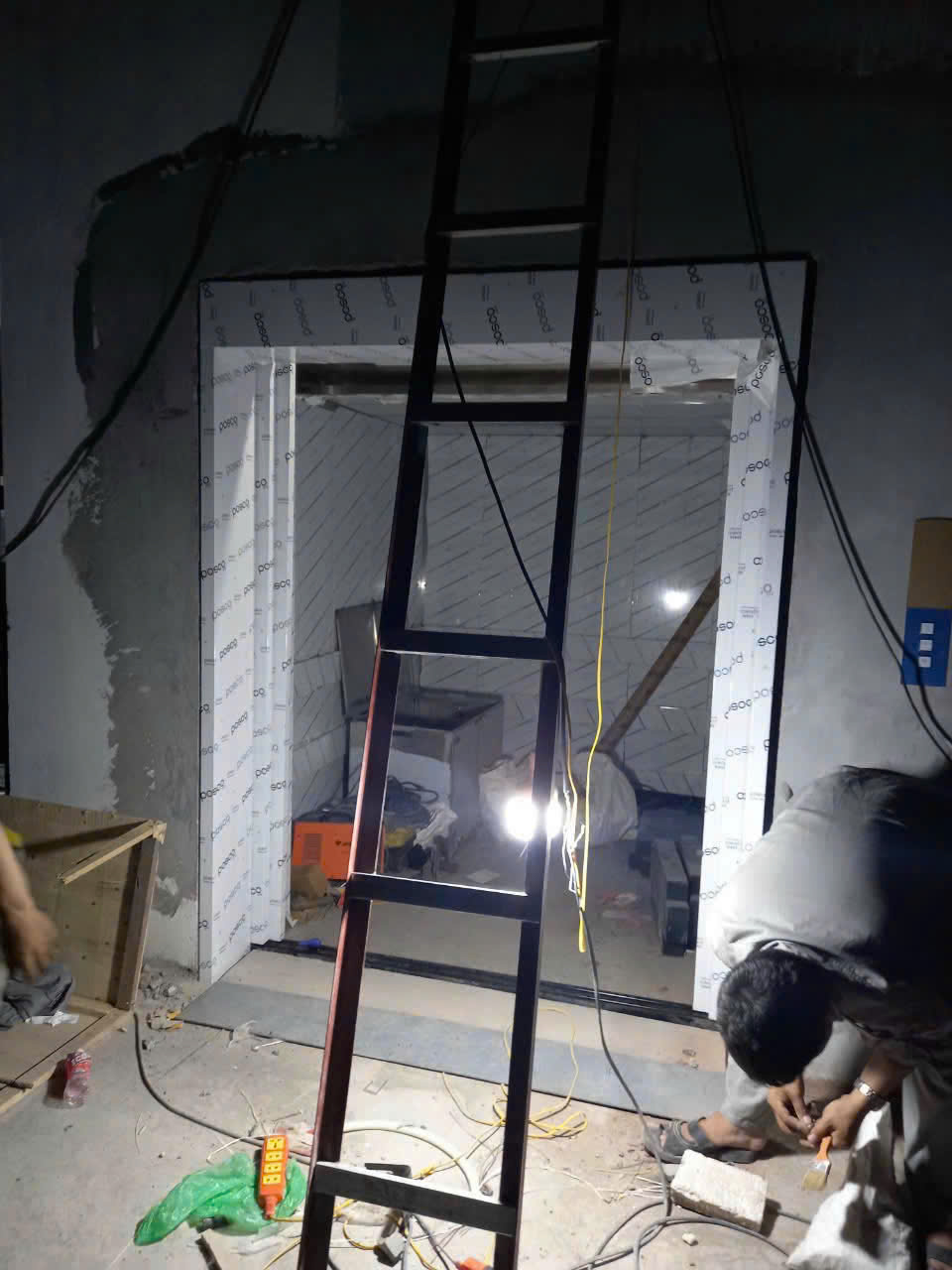 Thi công lắp đặt cửa thang máy trong nhà, thợ đang hoàn thiện khung và hệ thống điện